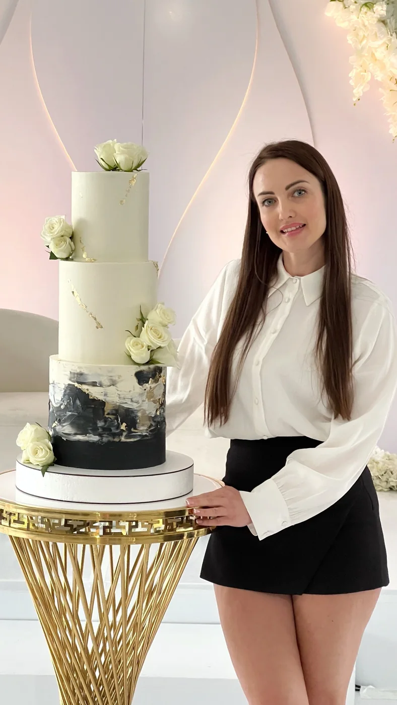 Black and white tiered wedding cake with white roses and gold accents