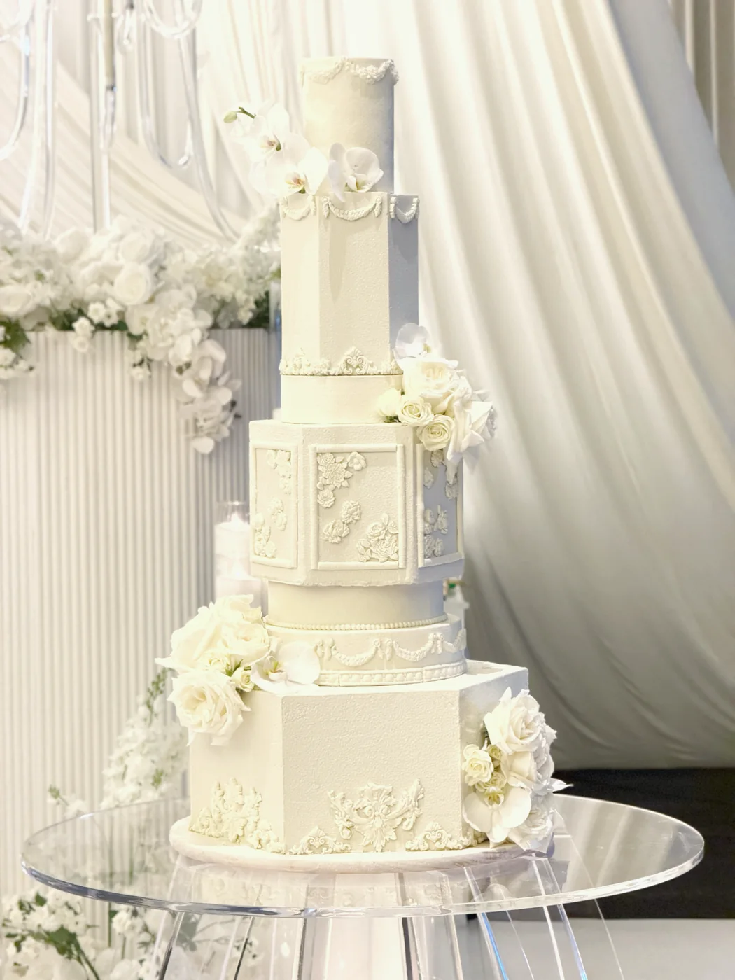 Fully edible ornate white wedding cake with sculpted floral details
