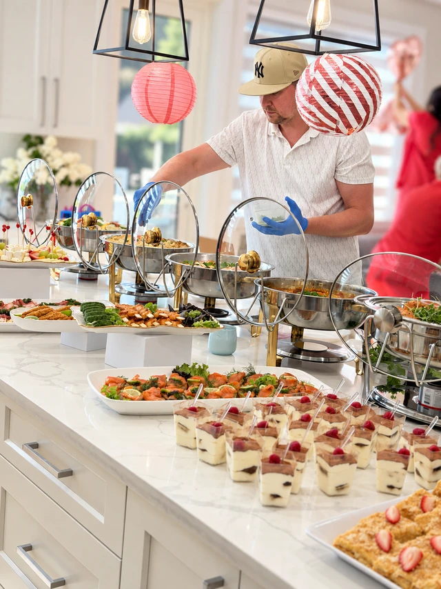 Catering team arranging a buffet of hot dishes, starters and desserts