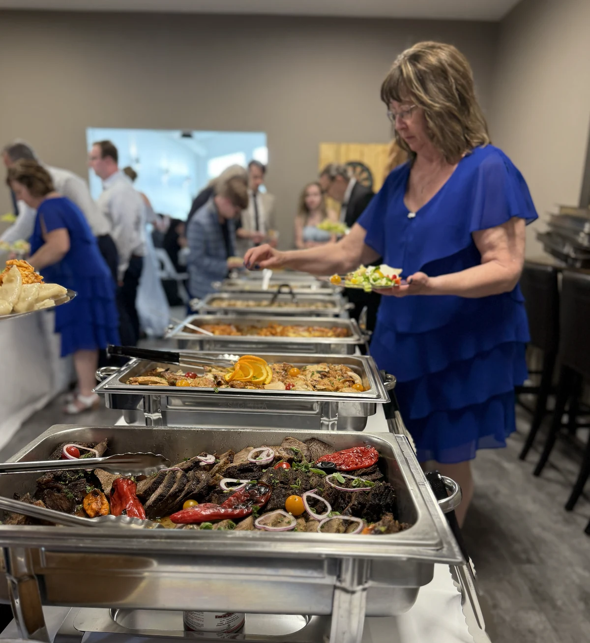 Wedding guest choosing freshly prepared buffet dishes at Tin Roof Event Centre in Lacombe, Alberta